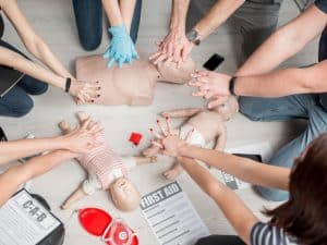 Basic life support training with group practising CPR on adult and infant manikins, emphasising essential first aid techniques.