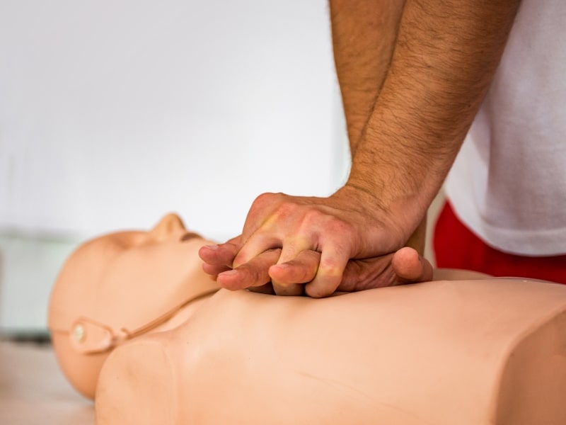 Basic life support training with hands performing chest compressions on a CPR mannequin, demonstrating emergency resuscitation techniques.