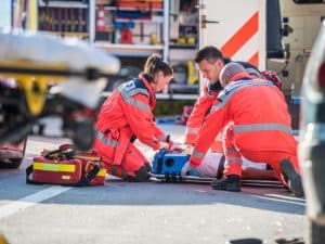 Emergency responders providing life saving first aid to an injured person at an accident scene.