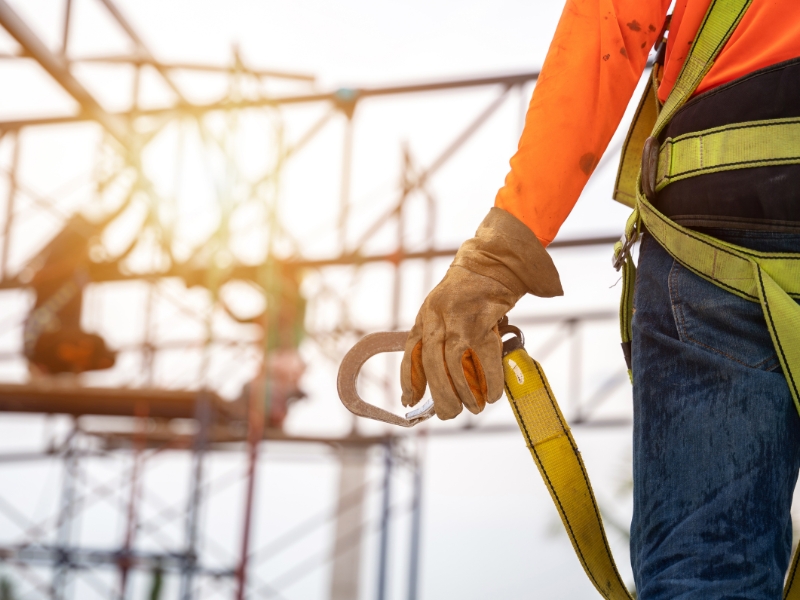 Worker using a fall prevention system with a harness and lanyard.