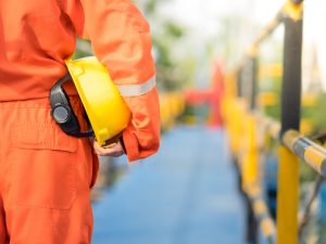 Worker holding a safety helmet on a construction site, highlighting precautions to prevent manual handling injuries in hazardous environments.