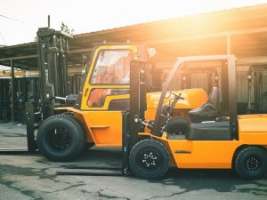 Two forklifts of different sizes parked outdoors, highlighting forklift weight limits for handling various load capacities in warehouses.