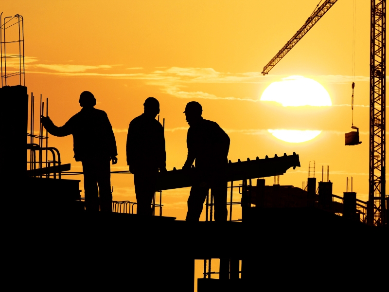 Construction site safety sign: 'White card required beyond this point.' Men in vests and helmets are visible.